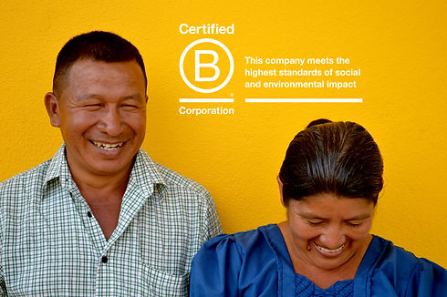 A man and woman of Central American descent laughing in front of a bright yellow wall