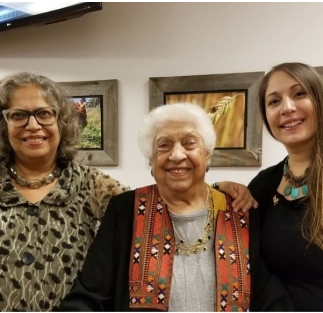 three generations of women of Ugandan/Indian heritage smiling happily into camera