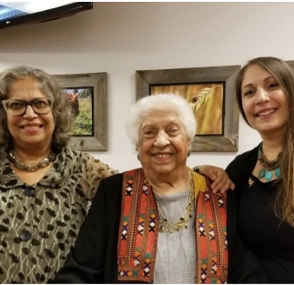 three generations of women of Ugandan/Indian heritage smiling happily into camera 