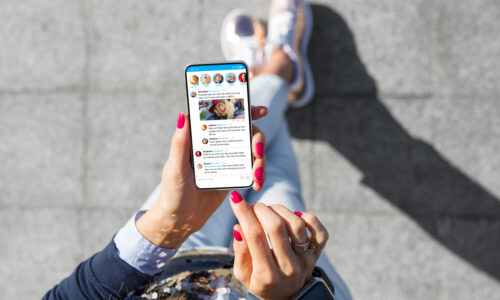Stock image of a woman looking at her social media feed on her phone