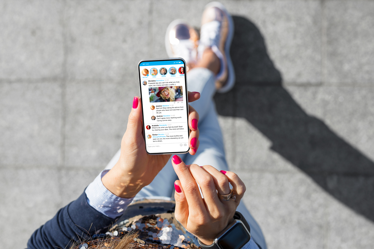 Stock image of a woman looking at her social media feed on her phone